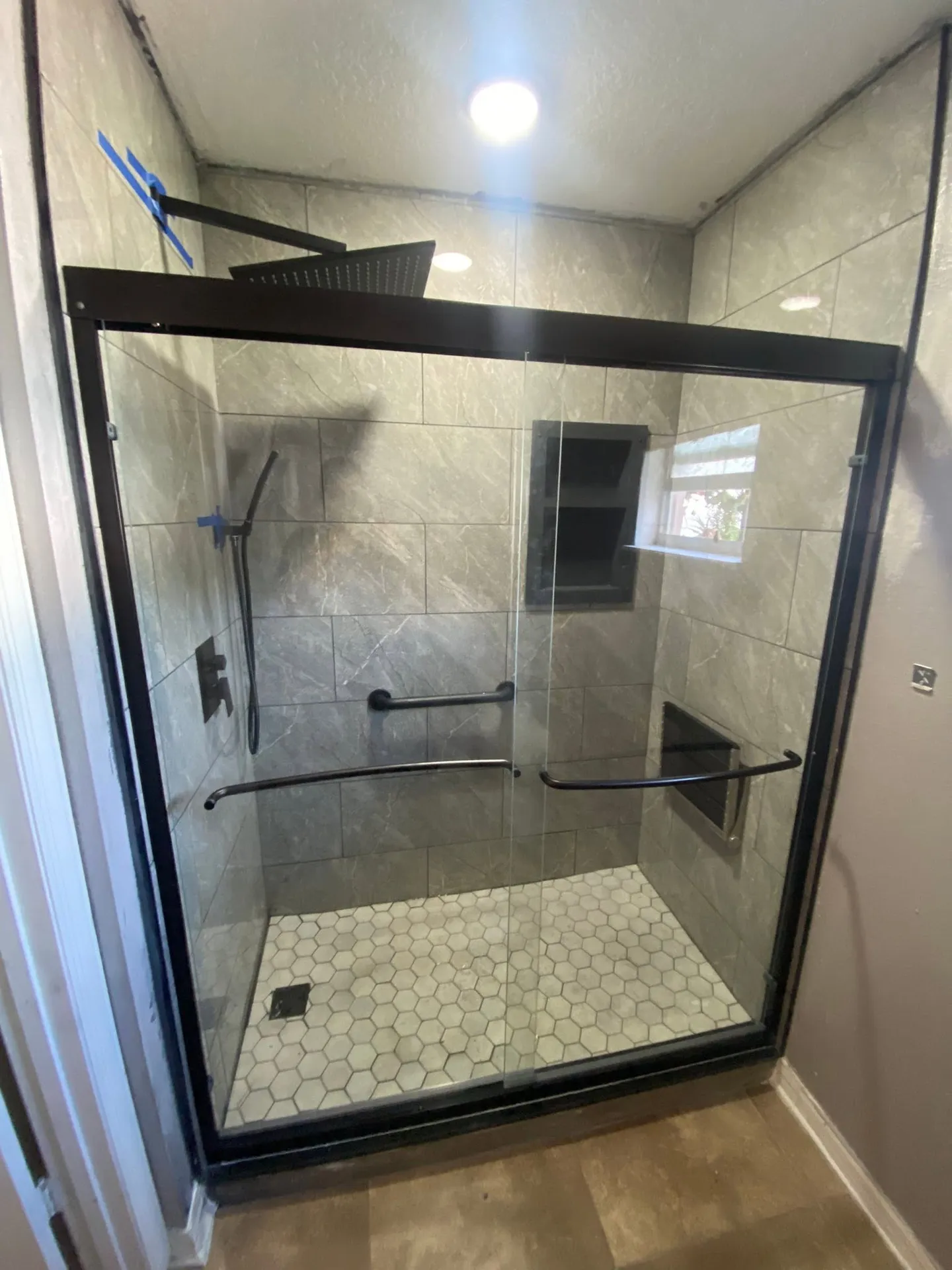 Shower during remodeling and with the finished glass enclosure.