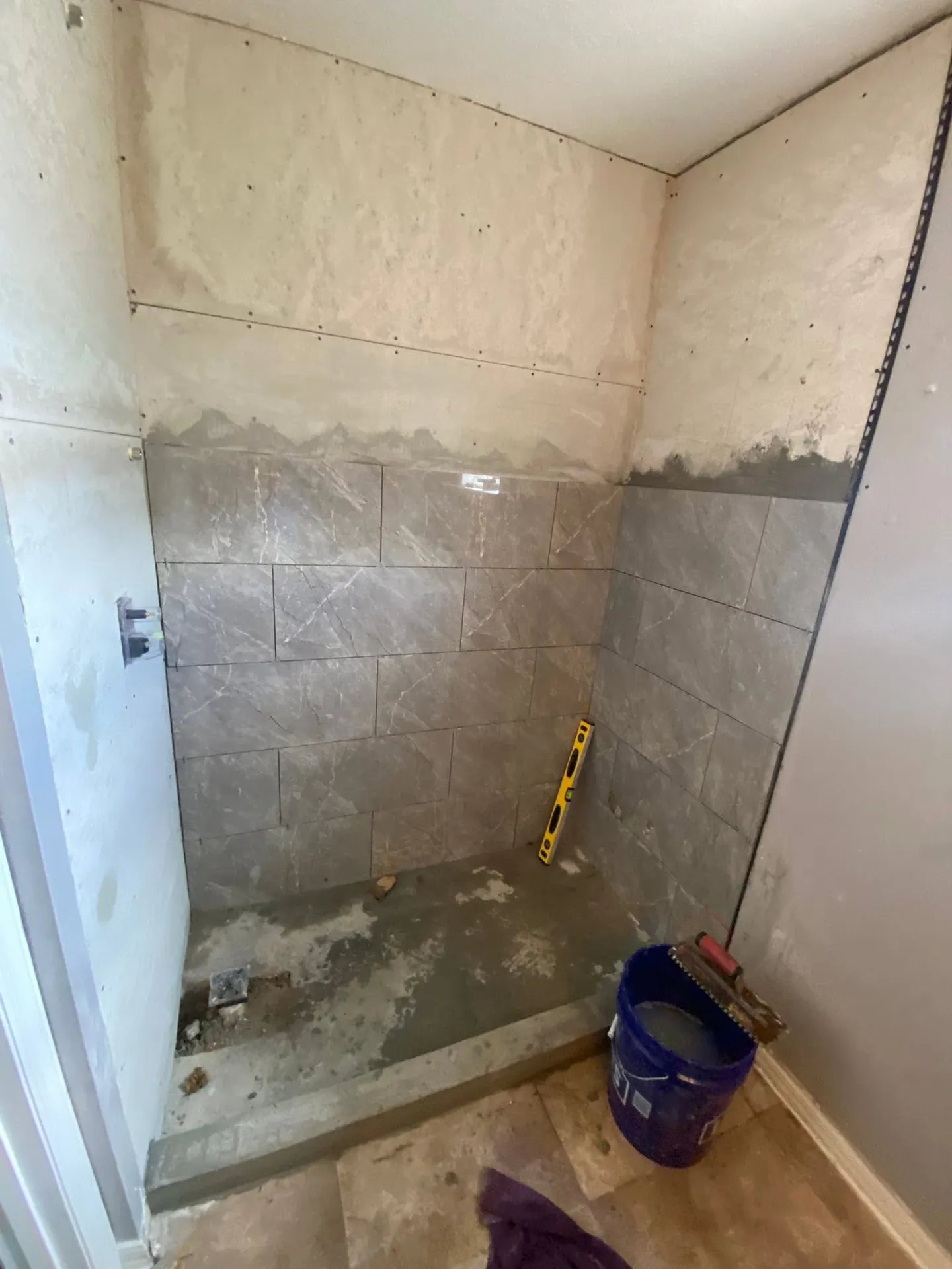 Shower during remodeling and with the finished glass enclosure.